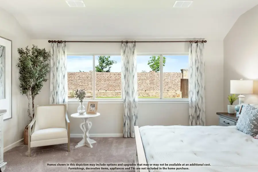 Bedroom with carpet flooring, large windows with patterned curtains, and a sitting area with accent chair