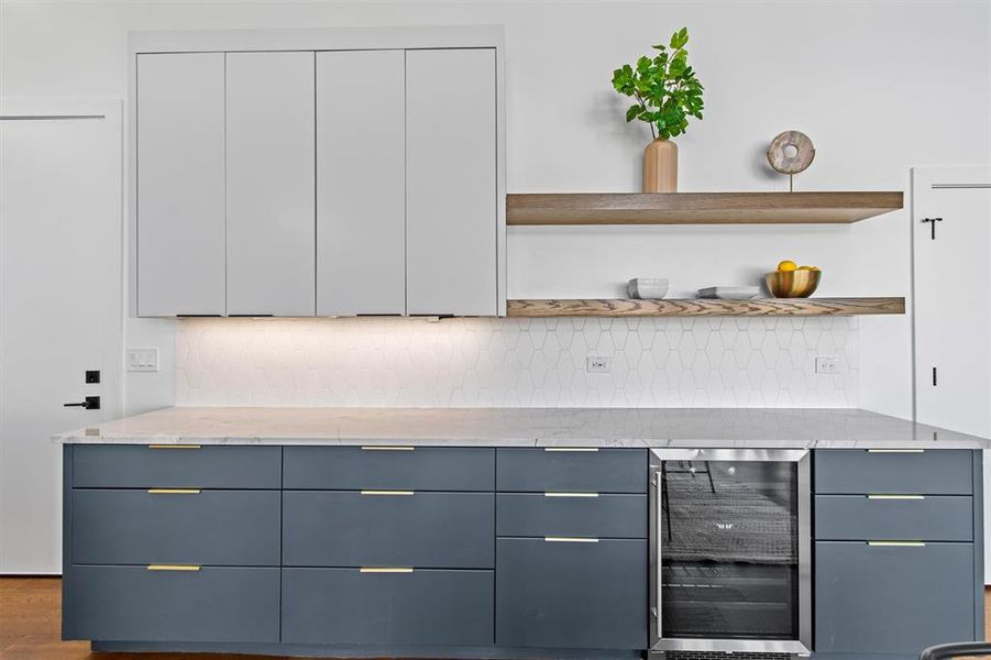 A modern wet bar area with sleek cabinetry and floating shelves, perfect for entertaining in style.