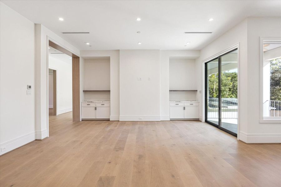 Game room includes built-in cabinetry and shelving with abundant lighting.