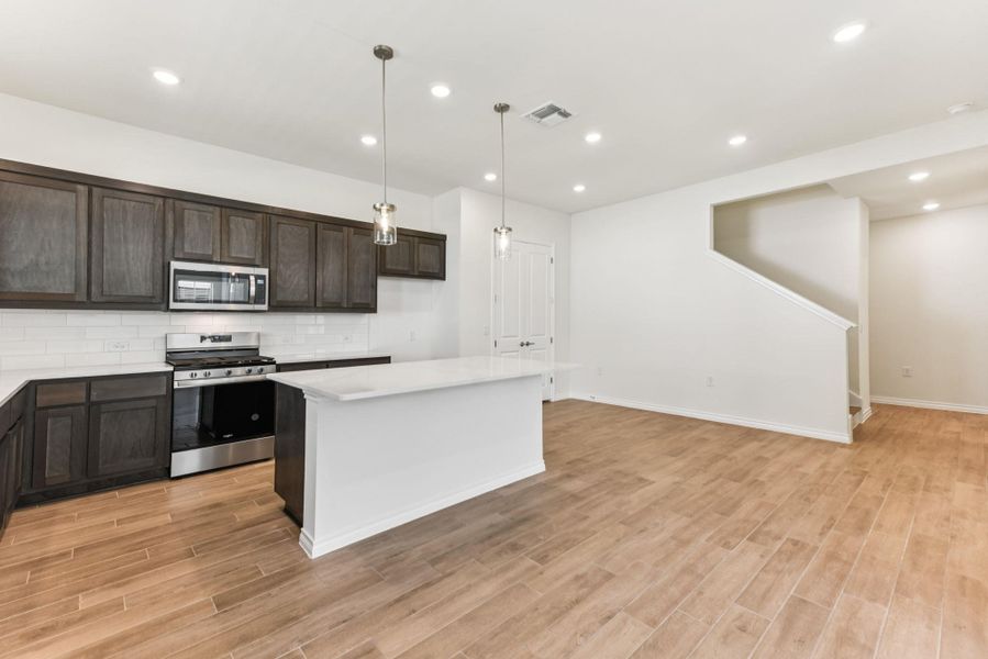 Kitchen featuring appliances with stainless steel finishes, decorative backsplash, a kitchen island, dark brown cabinets, and recessed lighting Kitchen featuring appliances with stainless steel finishes, decorative backsplash, a kitchen island, dark brown cabinets, and recessed lighting