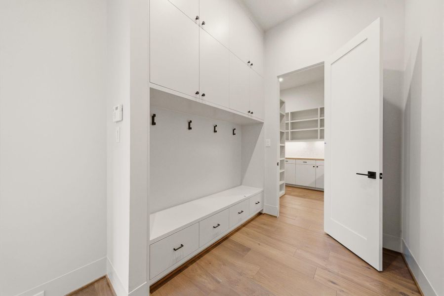 Custom mudroom with built-in storage, bench seating, and clean modern cabinetry. Near garage.