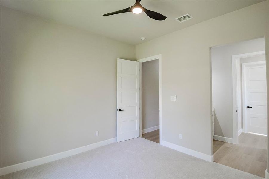 Unfurnished bedroom featuring light carpet and ceiling fan Unfurnished bedroom featuring light carpet and ceiling fan