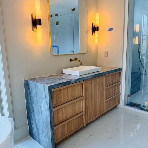 One of two separate vanities in the primary suite, each with its own moment. Veined stone, warm wood tones, and a faucet bent in just the right place. One of two separate vanities in the primary suite, each with its own moment. Veined stone, warm wood tones, and a faucet bent in just the right place.