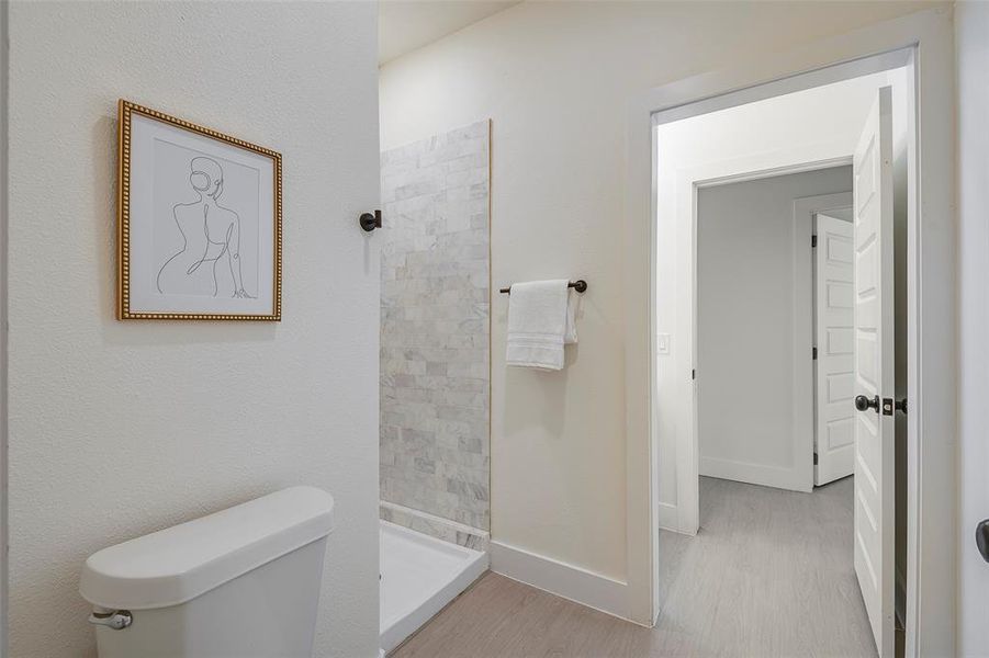 Bathroom featuring toilet, a tile shower, and hardwood / wood-style flooring