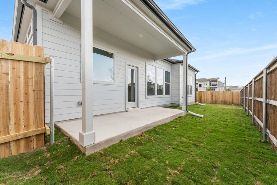 A private, grassy yard extends from the concrete patio, fully enclosed by a robust wooden fence. A private, grassy yard extends from the concrete patio, fully enclosed by a robust wooden fence.