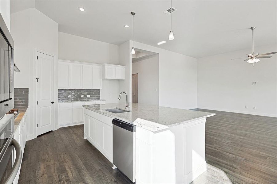 Kitchen featuring an island with sink, white cabinetry, stainless steel appliances, light stone counters, and dark hardwood / wood-style floors