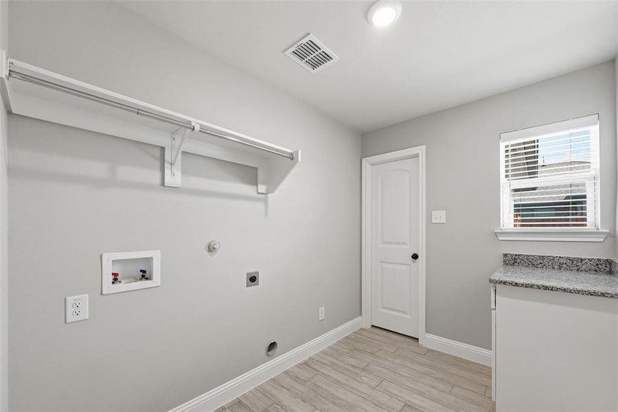 Laundry area featuring gas dryer hookup, light wood-style flooring, hookup for a washing machine, and hookup for an electric dryer Laundry area featuring gas dryer hookup, light wood-style flooring, hookup for a washing machine, and hookup for an electric dryer