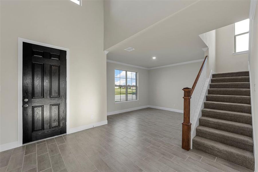 Entryway with wood tiled floors, stairs, crown molding, recessed lighting, and a high ceiling Entryway with wood tiled floors, stairs, crown molding, recessed lighting, and a high ceiling