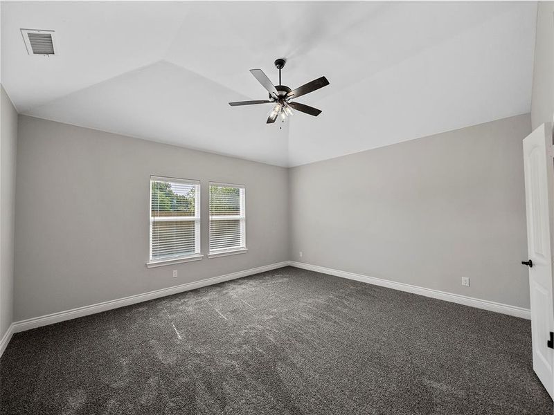 Empty room featuring lofted ceiling, carpet flooring, and a ceiling fan Empty room featuring lofted ceiling, carpet flooring, and a ceiling fan