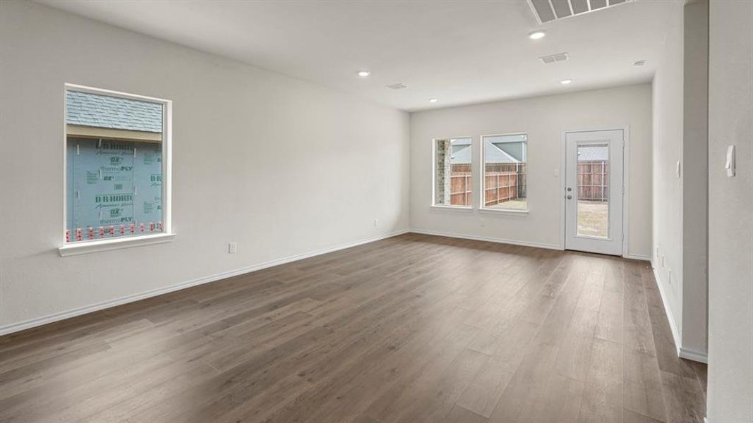 Spacious interior featuring wood-finish flooring, white walls, multiple windows, recessed lighting, and a glass-paned exterior door