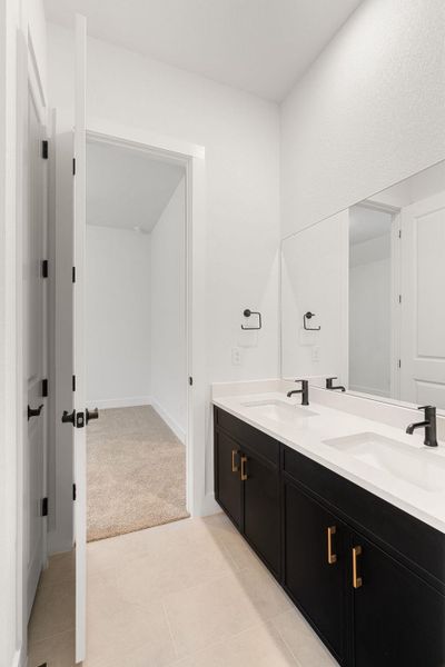 A well-lit bathroom features a long dual vanity with black cabinetry and a mirrored wall.