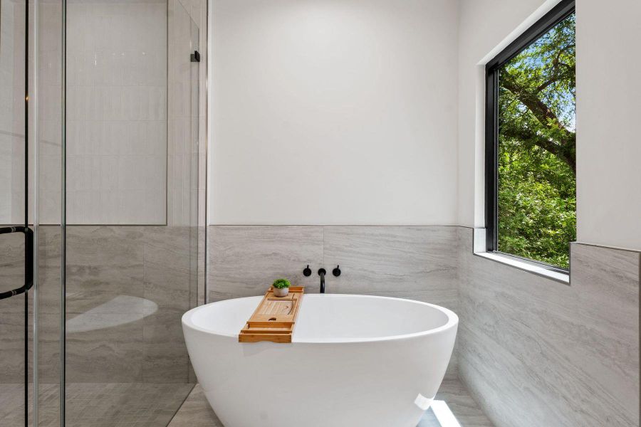 Indulge in a tranquil bathing experience with a sleek, freestanding tub and a view of verdant trees. Indulge in a tranquil bathing experience with a sleek, freestanding tub and a view of verdant trees.