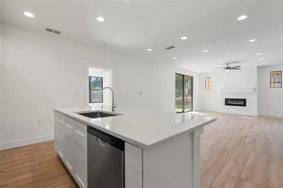 Kitchen featuring recessed lighting, dishwasher, a glass covered fireplace, light wood finished floors, and open floor plan