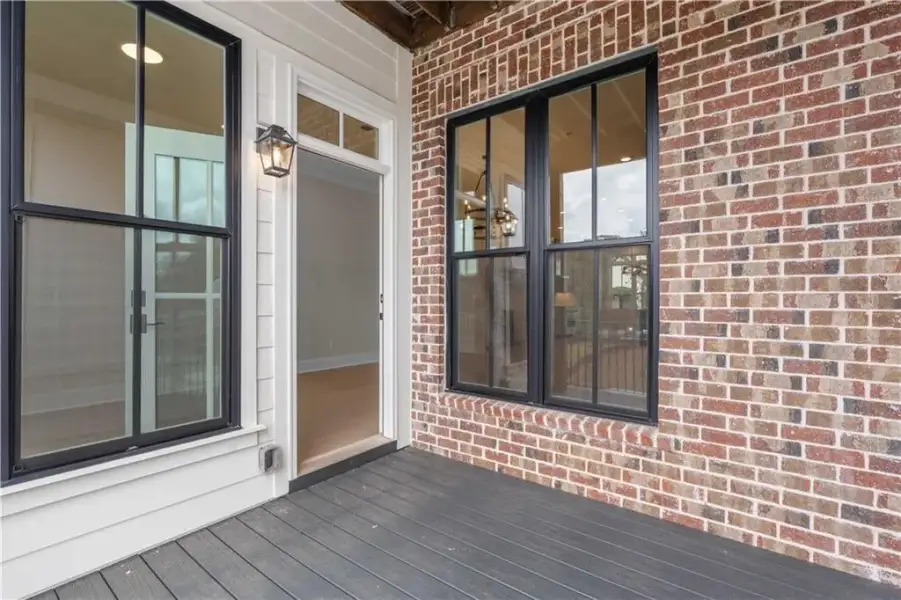 Exterior with brick facade, dark-frame windows, and a black composite deck