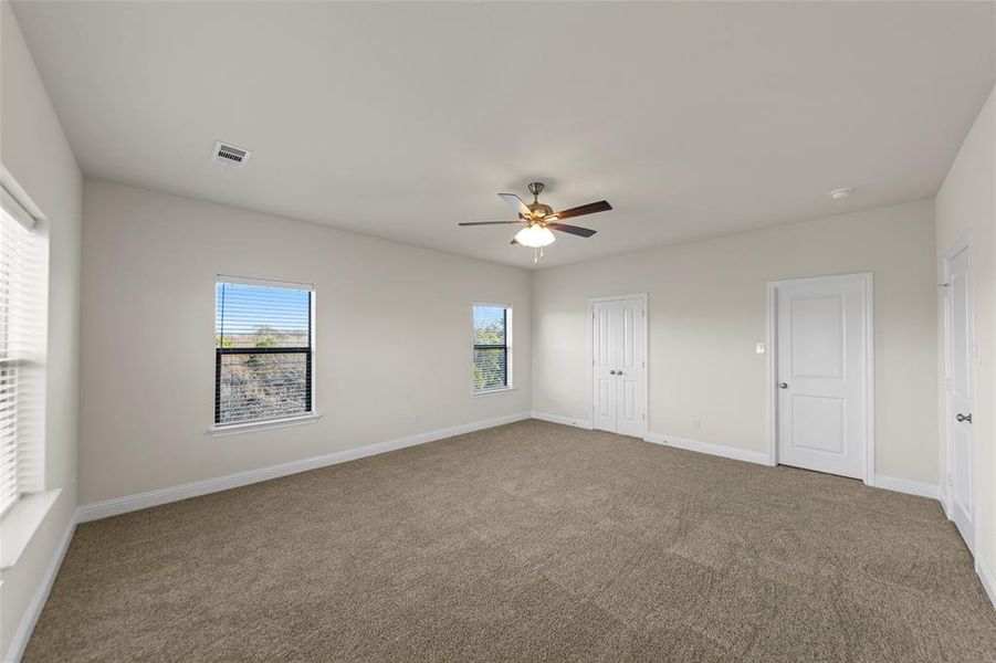 Unfurnished bedroom with carpet floors, a ceiling fan, multiple windows, and a closet