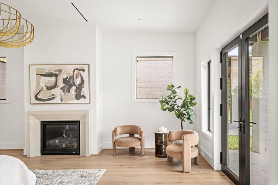 A closer look at the primary suite showcases the fireplace, natural light, and seamless connection to the outdoor patio.