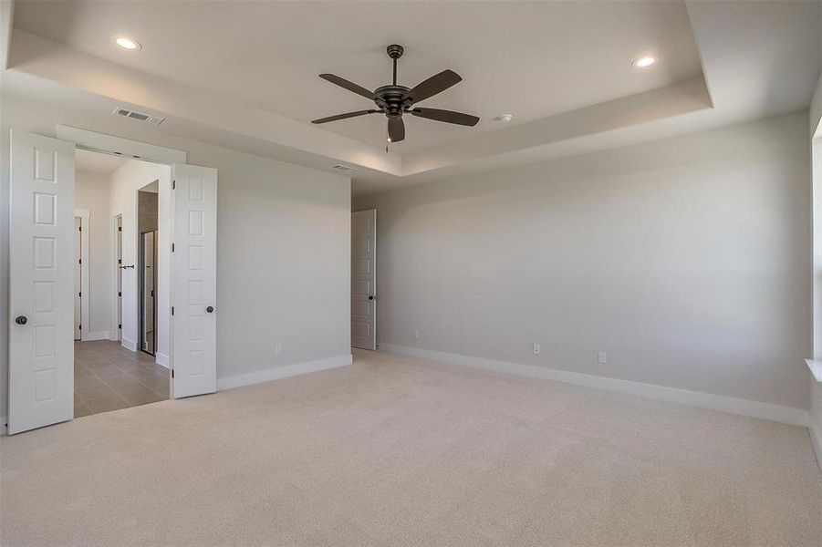 Spare room featuring visible vents, ceiling fan, carpet, a tray ceiling, and recessed lighting Spare room featuring visible vents, ceiling fan, carpet, a tray ceiling, and recessed lighting