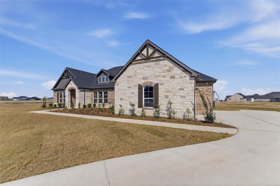 View of front of property featuring a front lawn, stone siding, a residential view, and brick siding View of front of property featuring a front lawn, stone siding, a residential view, and brick siding