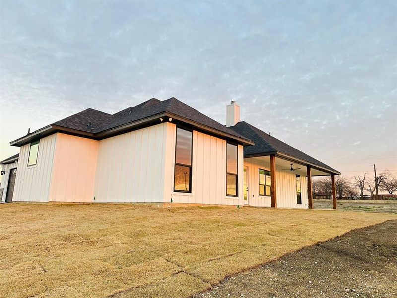 Rear view of property featuring ceiling fan and a lawn