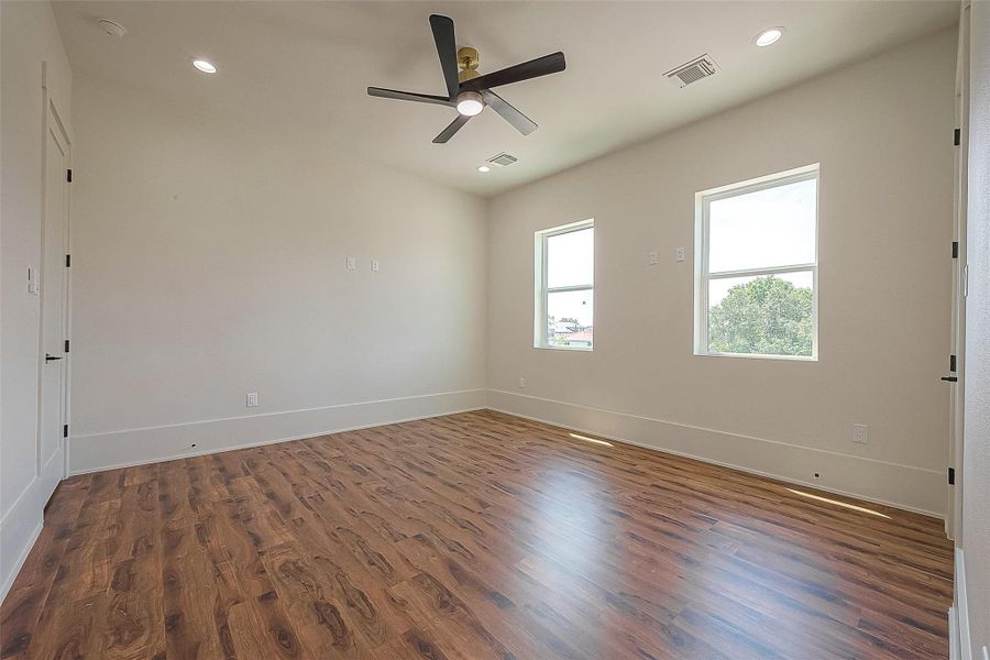 This is a bright, spacious room featuring wood flooring, two large windows offering natural light, a modern ceiling fan, and neutral wall colors ready for personalization. This is a bright, spacious room featuring wood flooring, two large windows offering natural light, a modern ceiling fan, and neutral wall colors ready for personalization.