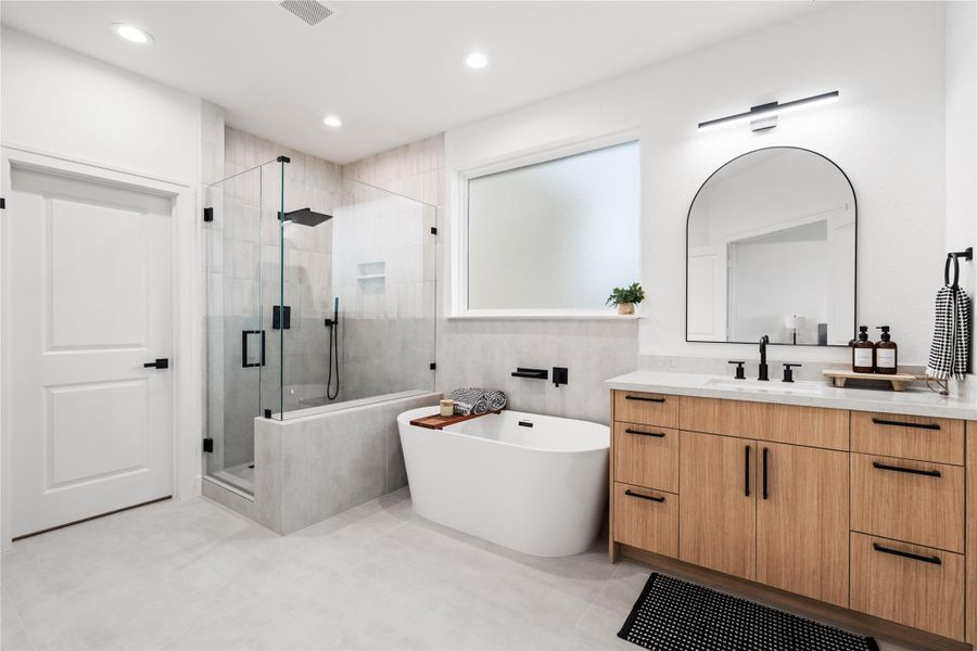 The spa-like ensuite exudesquiet luxury, featuring dualvanities framed in warm woodtones and a statementfreestanding tub.