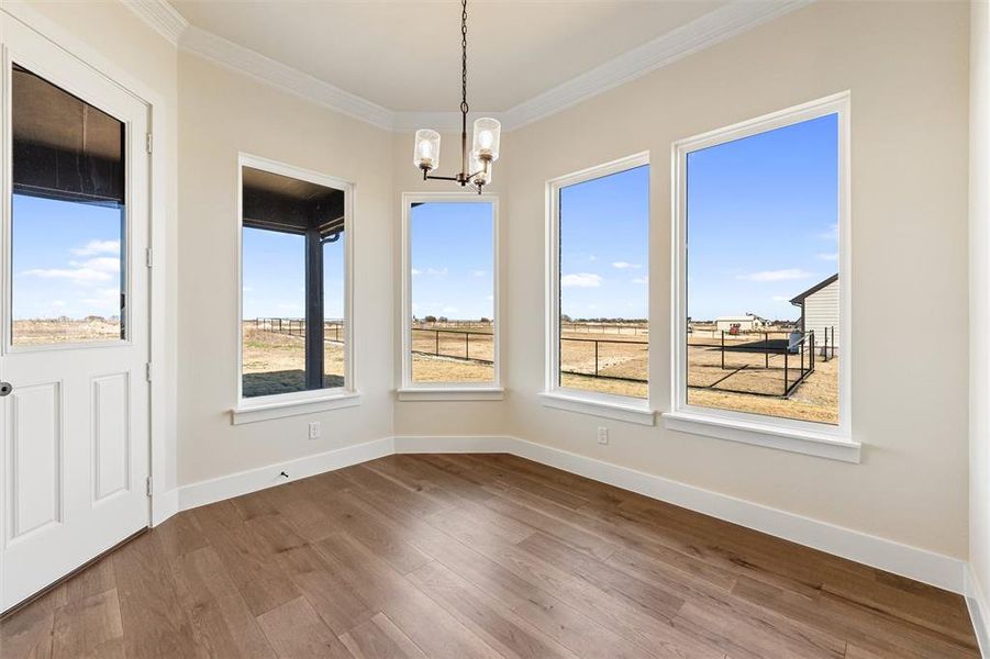 Unfurnished dining area with wood finished floors, ornamental molding, and a chandelier