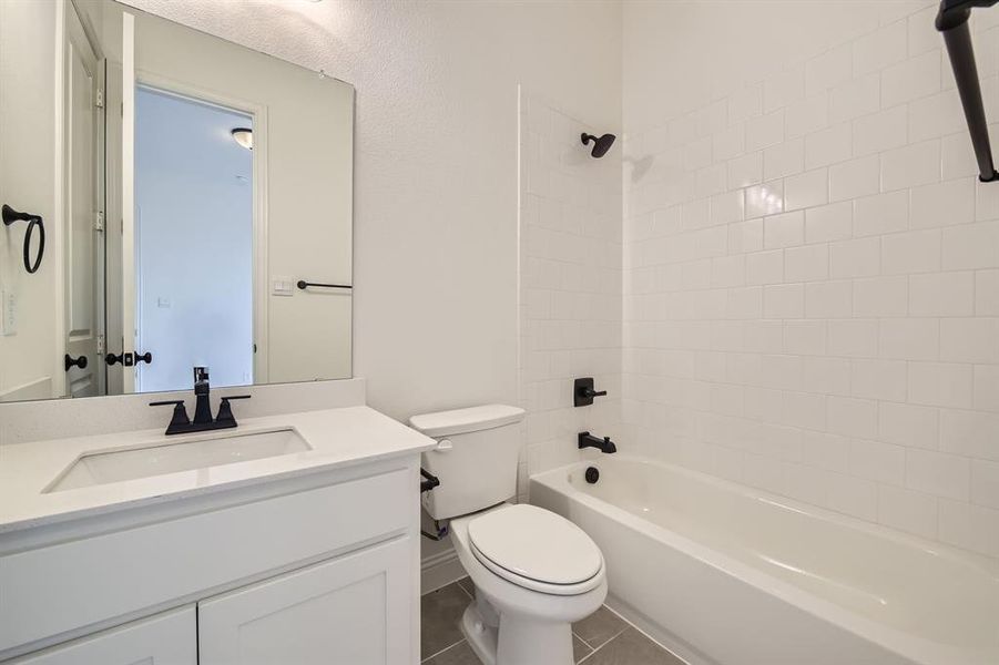 Full bathroom with tile patterned flooring, tiled shower / bath, vanity, and toilet