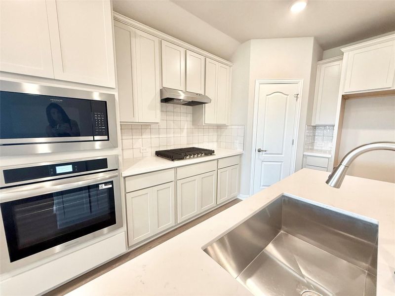 Kitchen with stainless steel appliances, backsplash, white cabinetry, light stone countertops, and recessed lighting Kitchen with stainless steel appliances, backsplash, white cabinetry, light stone countertops, and recessed lighting