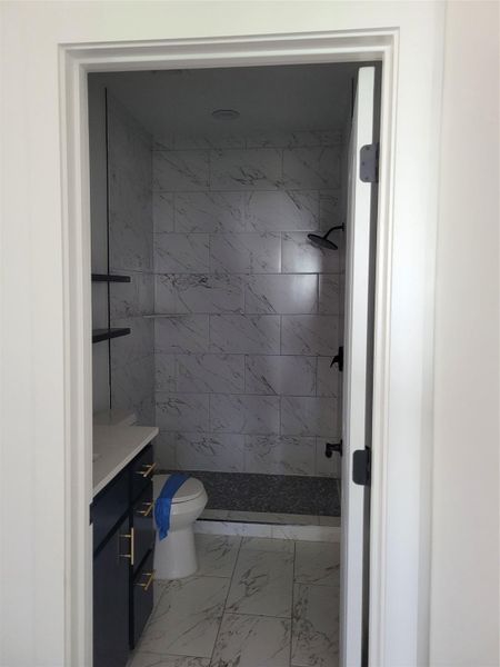 Bathroom with vanity, a shower stall, and light marble finish flooring