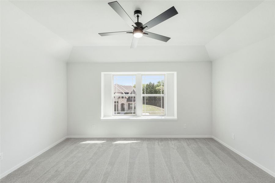 Empty bedroom with vaulted ceiling, ceiling fan, gray carpet, and double window with neighborhood view Empty bedroom with vaulted ceiling, ceiling fan, gray carpet, and double window with neighborhood view