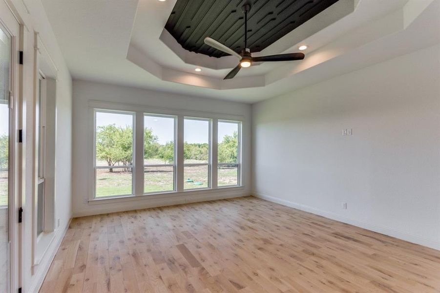 Game room  with light wood-type flooring, ceiling fan, and a raised ceiling