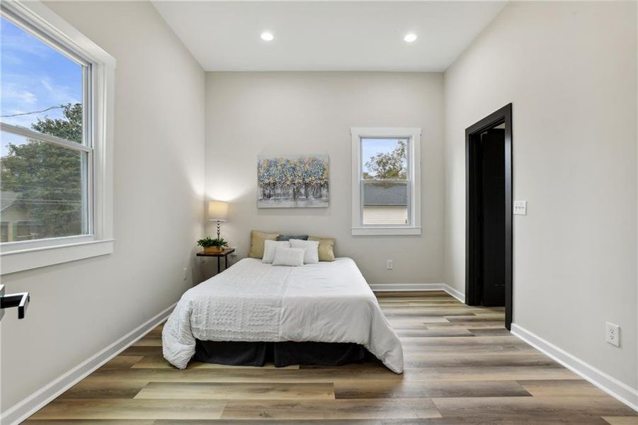 Bedroom with multiple windows and Luxury Vinyl Plank flooring