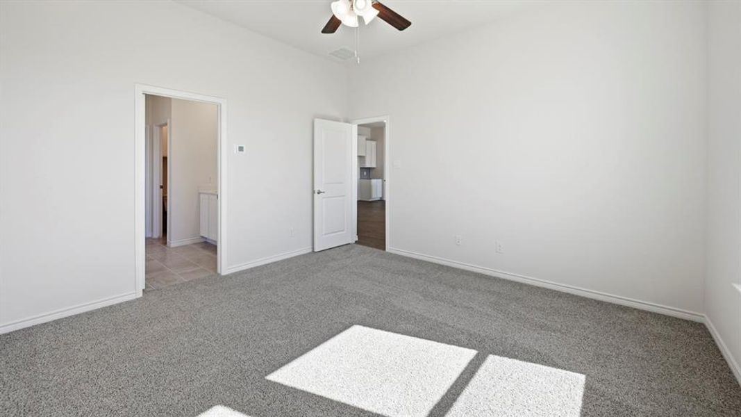 Spacious room featuring neutral carpeting, white walls, and a ceiling fan Spacious room featuring neutral carpeting, white walls, and a ceiling fan