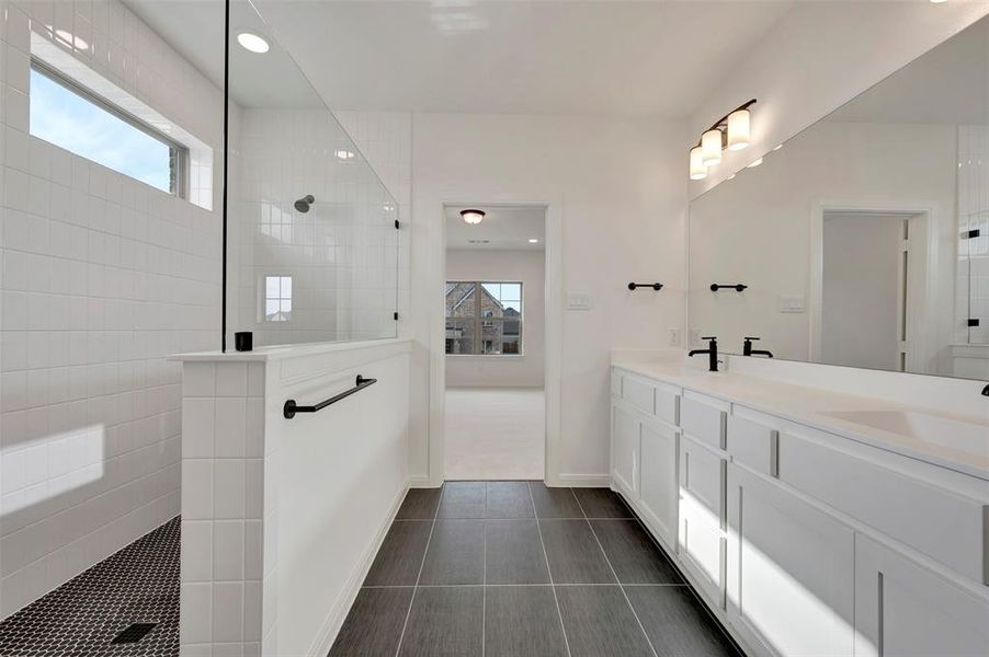 Full bath with walk in shower, double vanity, recessed lighting, and dark tile patterned floors