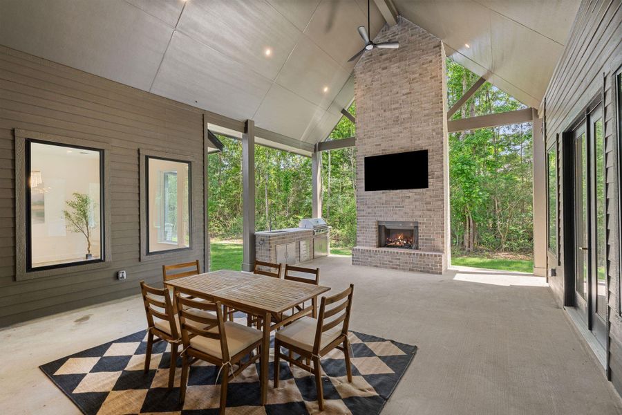 Show-stopping covered outdoor living space with soaring vaulted ceiling and a floor-to-ceiling brick wood burning fireplace as the centerpiece. Expansive windows and glass doors bring in natural light and frame peaceful backyard views.