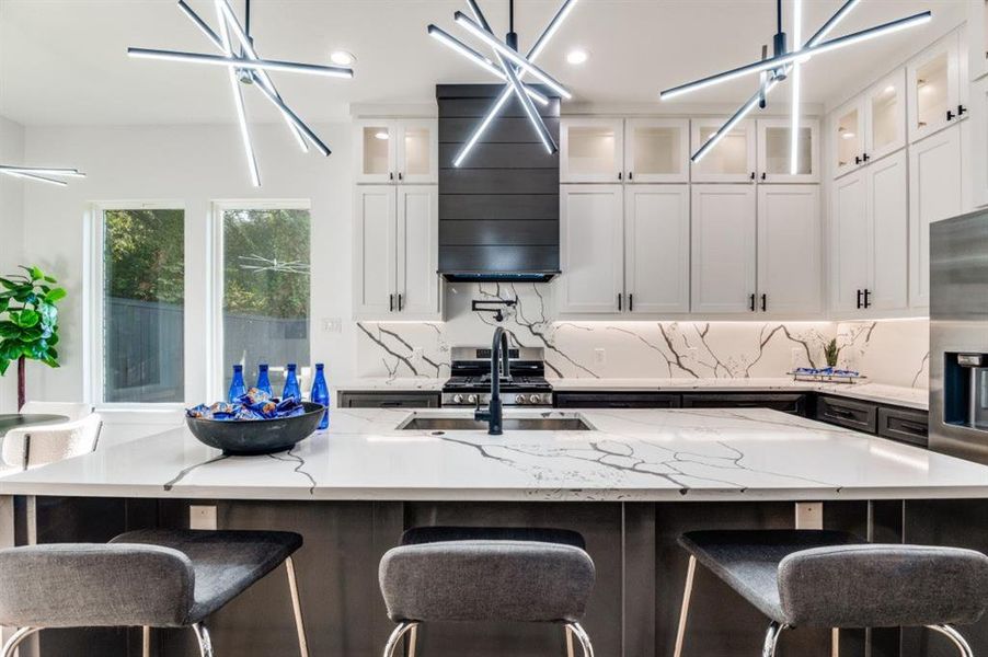 Kitchen with white cabinets, a kitchen bar, light stone countertops, decorative backsplash, and an island with sink Kitchen with white cabinets, a kitchen bar, light stone countertops, decorative backsplash, and an island with sink