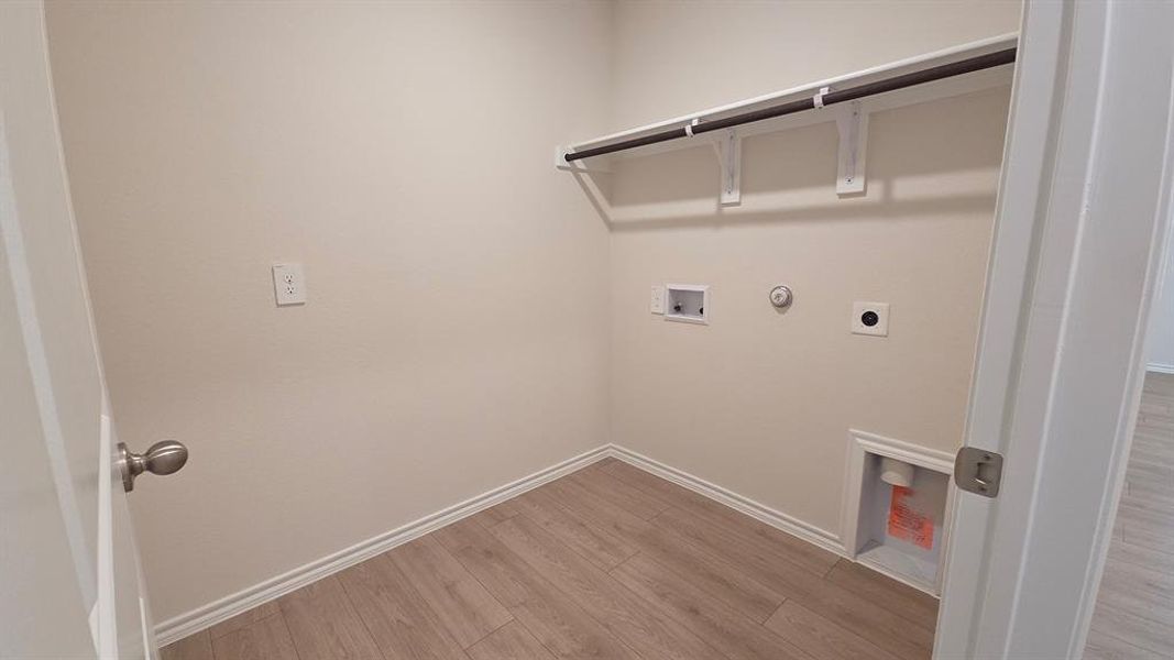 Utility room with wood-finish flooring, white baseboards, and neutral wall tones