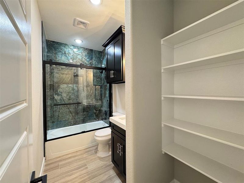 Contemporary bathroom featuring a tub and shower combination with a sliding glass door, a custom tiled surround, and recessed lighting