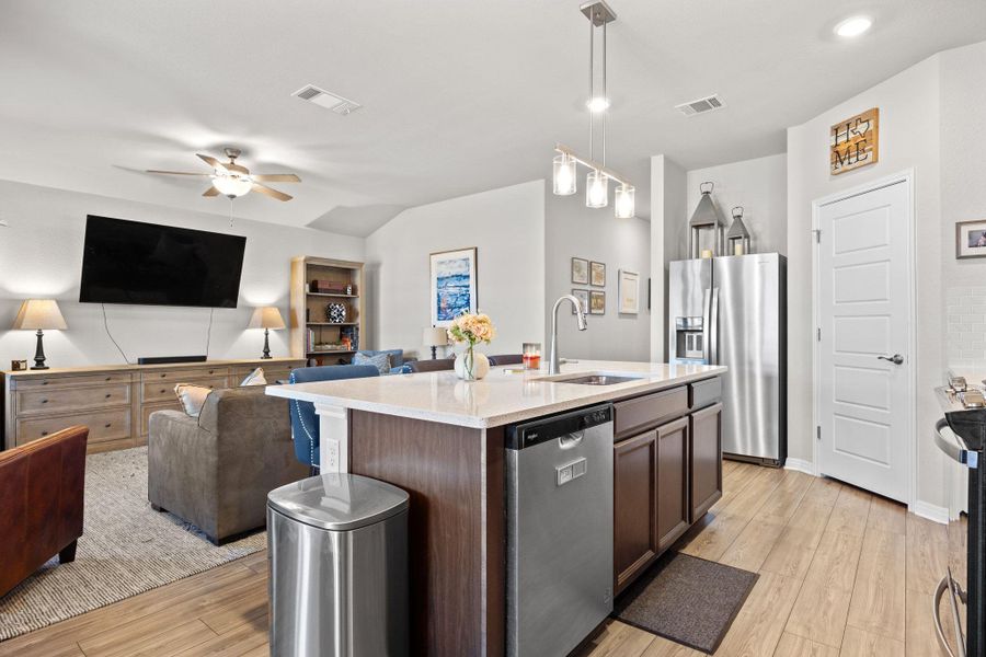 Kitchen featuring open floor plan, hanging light fixtures, stainless steel appliances, light wood-type flooring, and ceiling fan Kitchen featuring open floor plan, hanging light fixtures, stainless steel appliances, light wood-type flooring, and ceiling fan