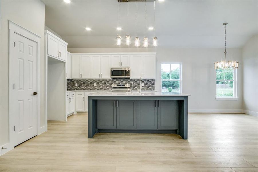 Kitchen featuring light countertops, stainless steel appliances, white cabinetry, and tasteful backsplash