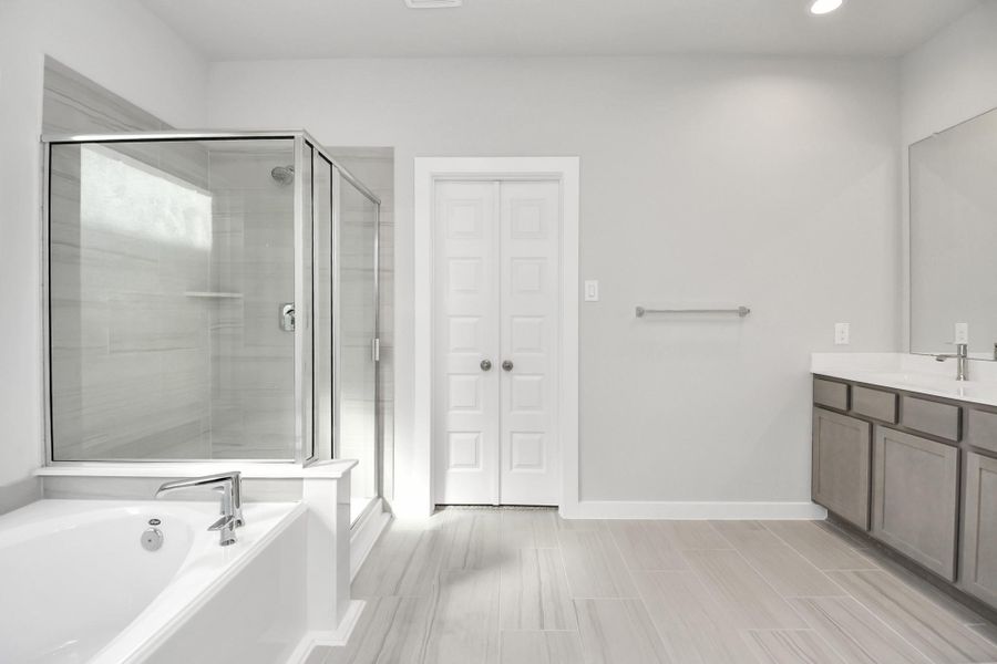 Indulge in a spa-like retreat within the confines of this primary bathroom.Delight in a spacious walk-in shower enveloped in stylish tile surround, unwindin a separate garden tub adorned with custom detailing, and elevate your dailyroutine at the elegant vanity. Sample photo of completed home with similar floor plan. Actual colors and selections may vary.