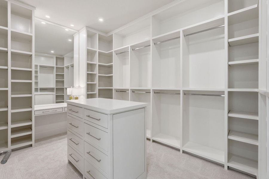 Dream-worthy primary closetfeaturing wall-to-wall customshelving, dual hanging zones, aseated vanity area and aspacious island that elevateseveryday organization.