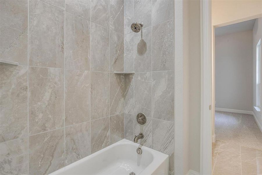 Bathroom featuring tiled shower / bath combo and tile patterned flooring