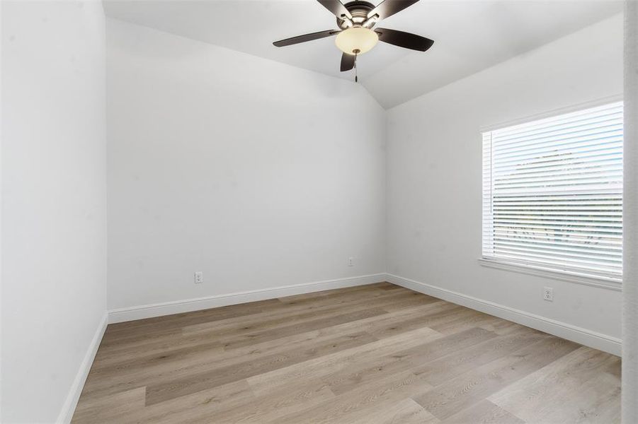 Empty room with light wood-style flooring, ceiling fan, and vaulted ceiling Empty room with light wood-style flooring, ceiling fan, and vaulted ceiling