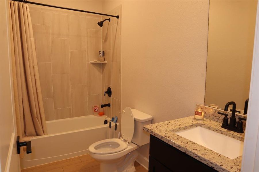 Bathroom with shower / bathtub combination with curtain, vanity, and light wood-style flooring Bathroom with shower / bathtub combination with curtain, vanity, and light wood-style flooring