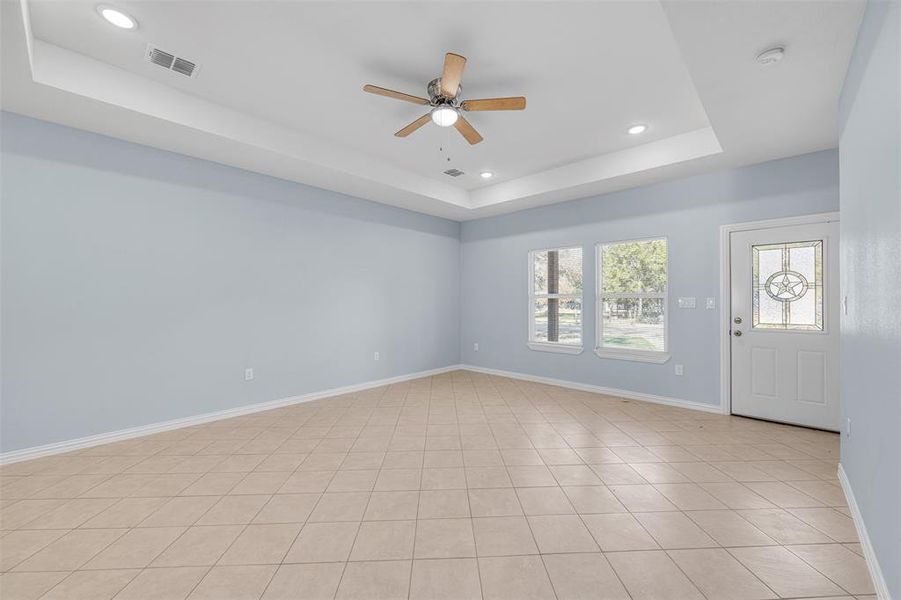 Unfurnished room featuring light tile patterned floors, a raised ceiling, and ceiling fan