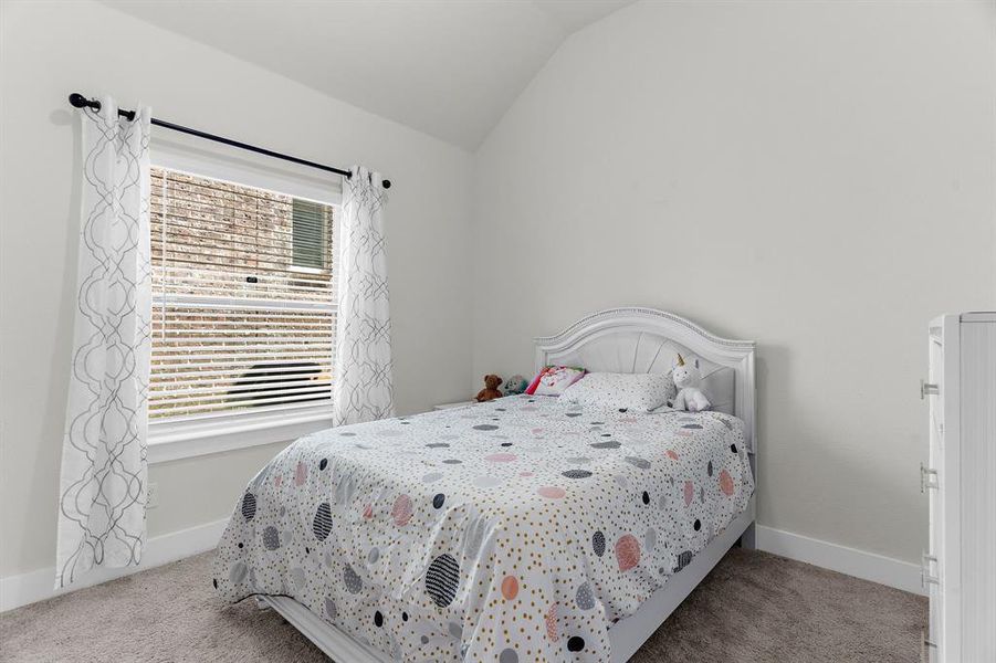 Bedroom with carpet floors, vaulted ceiling, and baseboards Bedroom with carpet floors, vaulted ceiling, and baseboards