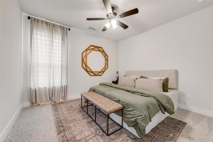 Bedroom featuring light-toned walls, carpeted flooring, and a ceiling fan with integrated lighting