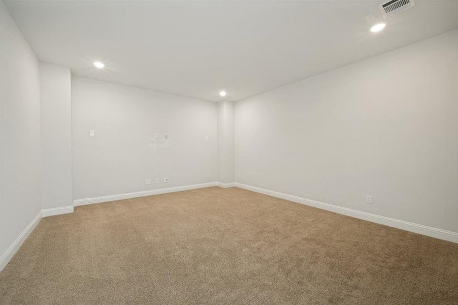 Spacious room featuring neutral carpeting, light-colored walls, white baseboards, and recessed lighting