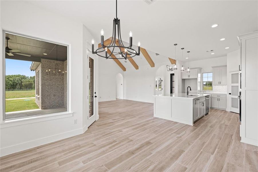 Kitchen featuring a chandelier, arched walkways, open floor plan, a kitchen island with sink, and hanging light fixtures Kitchen featuring a chandelier, arched walkways, open floor plan, a kitchen island with sink, and hanging light fixtures